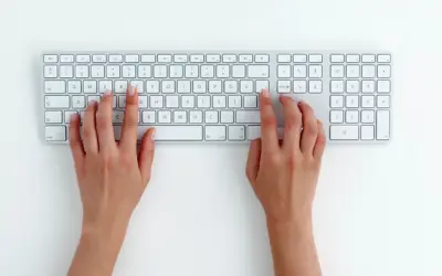 Hands typing on white keyboard