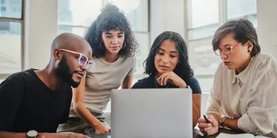 Team working together on a laptop looking at the screen intently