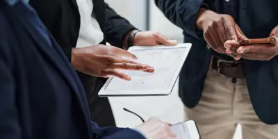 Three office people standing together looking at a tablet